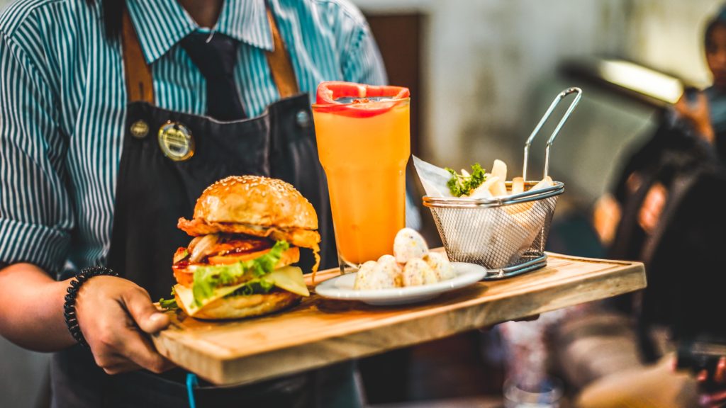 Waiter holding a tray of food in a beautifully captured Southern California restaurant, highlighting the importance of architectural photography.