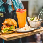 Waiter holding a tray of food in a beautifully captured Southern California restaurant, highlighting the importance of architectural photography.