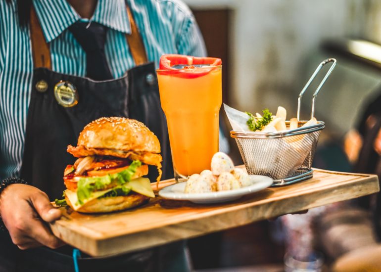 Waiter holding a tray of food in a beautifully captured Southern California restaurant, highlighting the importance of architectural photography.